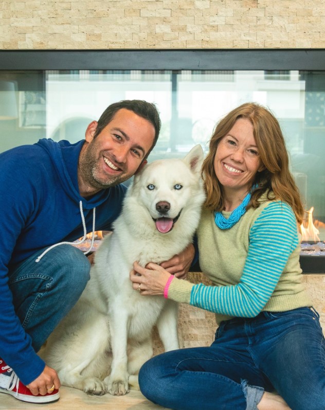 a man and a woman take a picture with a white dog